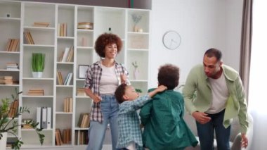 Gündelik giysiler içinde çok ırklı bir aile. Parlak şık bir dairede takılıp müzik dinliyorlar. Kaygısız anne, baba ve dans eden, zıplayan ve eğlenen iki çevik çocuk..