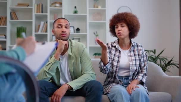 沮丧的非洲裔美国夫妇在婚姻危机期间与家庭心理学家进行治疗 穿着休闲装的年轻夫妇坐在沙发上谈情说爱 — 图库视频影像
