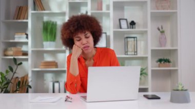 Ofis masasında kablosuz bilgisayarın önünde otururken yorgun Afrikalı Amerikalı kadın uykulu ve sıkılmış hissediyor. Motivasyon eksikliği ve sevilmeyen monoton iş konsepti.