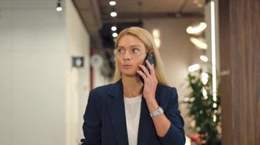 Resmi giyinen güzel iş kadını ofis dışından telefon ettiği için işten izin alıyor. Elli saati olan gülümseyen mavi gözlü kadın modern akıllı telefonda hoş sohbetler yapıyor..