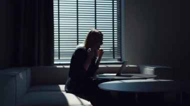 Takım elbiseli kadın işveren dizüstü bilgisayara bakıyor ve mutluluktan duygusal olarak el kol hareketi yapıyor. Beyaz kadın ofis masasında otururken iş projesinde başarı hakkında harika haberler alıyor..