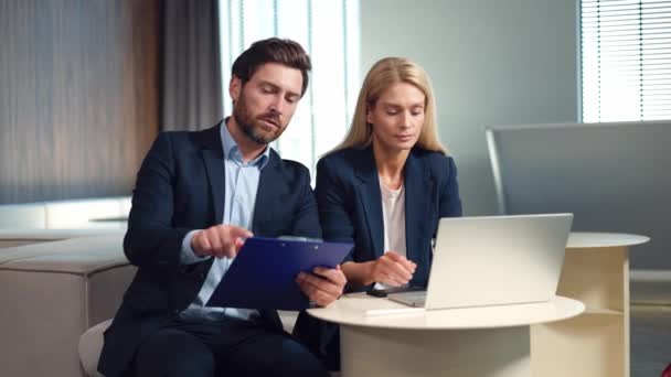 Handsome Bearded Man Pointing Blue Clipboard While Sitting Female Assistant — Stock Video