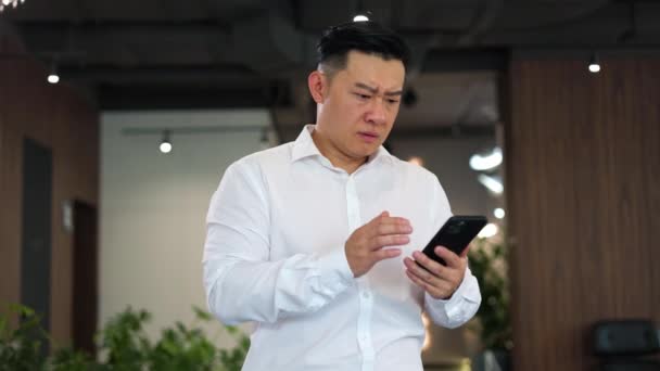 Šokovaný Muž Asijské Národnosti Čte Smartphonu Hrozné Zprávy Bankrotu Slavného — Stock video