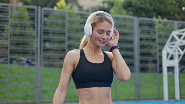 Kablosuz Kulaklıklarla Müzik Dinleyen Spor Figürlü Zayıf Beyaz Bir Kadın — Stok video