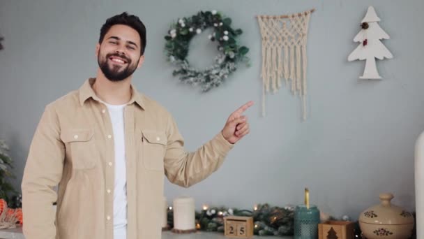 快乐的男人有着完美的微笑蓝眼睛 他们会在圣诞主题的厨房里模仿空间 旁边的树上会闪烁着花环 假日促销或冬季广告的理想环境 — 图库视频影像
