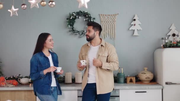 Νεαρό Ερωτευμένο Ζευγάρι Στέκεται Στην Κουζίνα Διακοσμημένο Για Χριστούγεννα Πίνοντας — Αρχείο Βίντεο