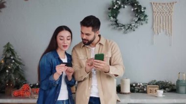 Akıllı telefondan alışveriş yapan beyaz çiftlerin portresi ve kredi kartıyla Noel satışlarının keyfini çıkarmak. Kadın internet tatil konseptinde kocasına satın alma hediyesi olarak CVV kodu veriyor.