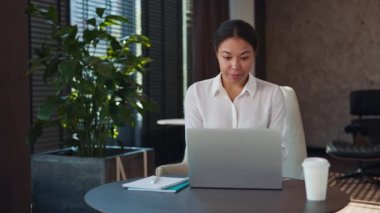 Beyaz bluzlu güzel olgun bir kadın, elinde notlar ve kahve fincanıyla ofis masasında oturmuş, kablosuz bilgisayarda yazı yazıyor. Kendine güvenen çok kültürlü iş kadını kameraya hoş bir gülümsemeyle bakıyor..
