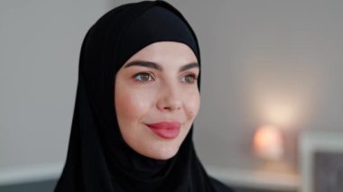 Siyah tesettürlü Arap kadının hayalperest, dalgın, odaklanmış yüzüne yakın çekim. Kafasında siyah başörtüsü olan feminist İslamcı kadının yüzü. İslam Ülkelerinde feminizm, Müslüman Feminist, eşit haklar.