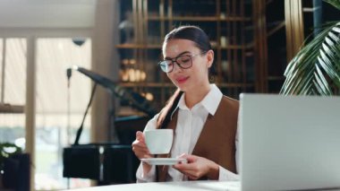 Profesyonel kıyafetli şık bir iş kadını zarif bir şekilde kokulu bir kapuçino, sofistike bir kafe veya restoranda kahvaltı, iş gezisi sırasında otel lobisi, lezzetli kremalı latte.