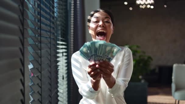 多种族女人面带微笑地看着相机 手里拿着一美元钞票的扇子 成功的女商人一边站在办公室窗前一边半闭着百叶窗 一边为自己的收入感到高兴 — 图库视频影像
