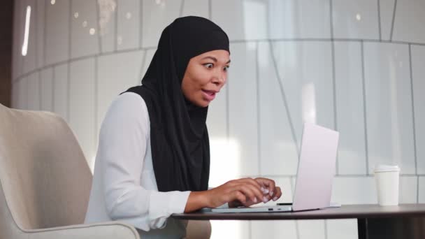 Mujer Africana Sorprendida Hijab Mirando Pantalla Del Ordenador Portátil Celebrando — Vídeo de stock