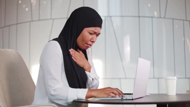 アフリカ系アメリカ人のビジネス女性は オフィスで無線ラップトップの仕事中に喉の痛みから咳をする 成熟した ヒジャブ ブラウス 持っている のために ストレス — ストック動画
