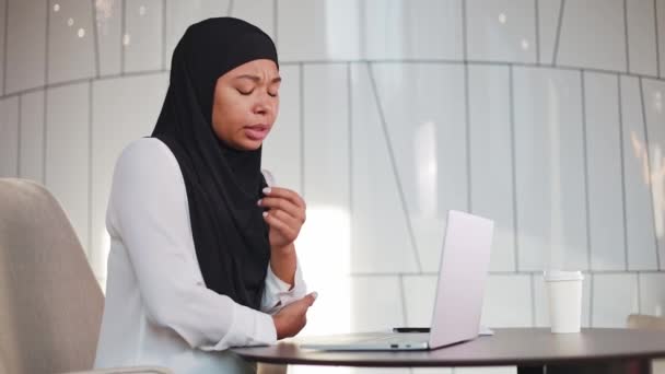 身披黑头巾的多种族妇女因在现代办公室长期工作而手肘酸痛 可悲的女经理坐在办公桌前 手里拿着无线笔记本电脑 手痛得很厉害 — 图库视频影像