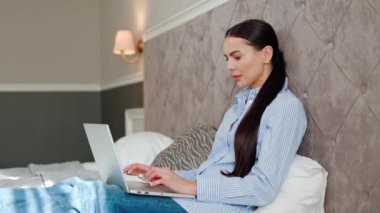Öfkeli genç kadın kullanıcı dizüstü bilgisayar kullanırken hayal kırıklığına uğruyor, yazılım hatası yüzünden kızgın, sosyal medyada kötü haber okumaktan endişeli, otel odasında oturuyor..