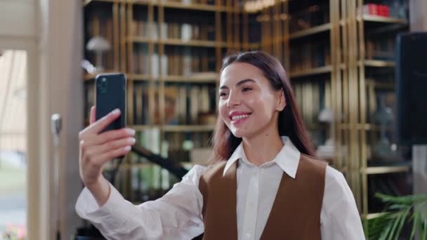 笑顔のビジネス女性が働いて 屋内レストランのビデオコールで話します ビジネスパートナーとのオンラインチャット 屋内での長距離通信 新しいアプリのスマートフォンを活用したレストランのオーナー — ストック動画