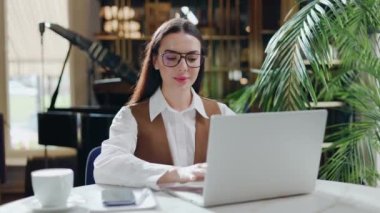 Gözlüklü bir iş kadını kafenin içinde modern dizüstü bilgisayarda daktilo kullanıyor. Çekici genç bir kız yönetici bilgisayar ekranına bakıyor. Restoranda oturuyor. Ciddi kadın şirket çalışanı internette sörf yapıyor..