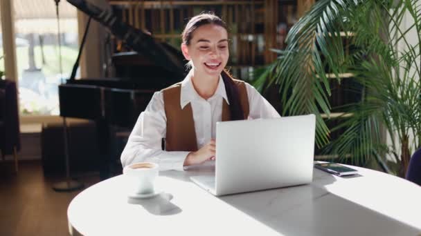 Trabajadora Sonriente Enfocada Sentada Restaurante Usando Portátil Inalámbrico Para Videollamadas — Vídeo de stock
