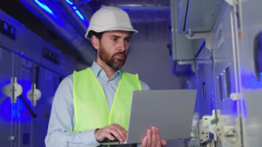 Konsantre erkek mühendis, kontrol merkezindeki güç ve motor mekanizmalarını yöneten, ağ ve sistem verimliliği açısından hayati önem taşıyan bir fabrika elektrik odasında çalışır. Sunucu odası, operatör istasyonu.