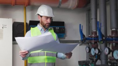 Mühendis ya da işçi, fabrikada çalışan tesisatçı. Çatıdaki soğutucu kule. Sistem çalışma makinesi. Yoğunlaştırıcı Su Tedarik boru hatları. İçerde proje kağıtları olan bir mühendisin portresi.