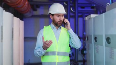 Kazan dairesinde teknik müdür telefonda konuşuyor. Bir kalite kontrol çalışanı tamamlanmış ısıtma görevlerini kontrol eder, göstergeleri doğrular, teknik odadaki kontrol sisteminden elde edilen verileri analiz eder.