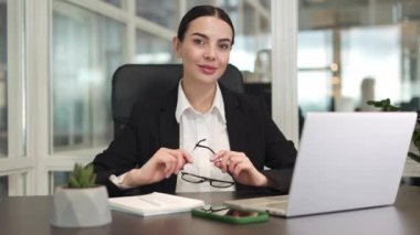 Siyah iş kıyafetleri içinde gülümseyen kadın girişimciler ofis koltuğunda oturup geniş bir odada ellerindeki bardakları tutarken dijital cihazlar kullanıyorlar. Başarı ve güven kavramı.