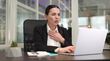 İşyerinde çalışan kadın bir ofis çalışanı kablosuz bilgisayarın önünde oturuyor ve ağzı mendille kaplıyken öksürüyor. Kafkasyalı esmer klavyede yazı yazıyor ve hastayken yeni ofiste çalışıyor..