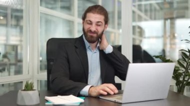 Modern ofiste otururken ve bilgisayarda yazı yazarken boynu ağrıyan ve acı çeken beyaz bir adam hayal kırıklığına uğradı. Meşgul erkek, sağlık sorunlarına rağmen çalışmaya devam ediyor.