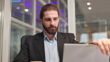 Odaklanmış orta yaşlı işadamı, modern aletini ofiste sıkı çalışma gününde açıyor. Resmi takım elbiseli şık bir insan dijital teknolojinin yardımıyla yönetimini geliştiriyor..