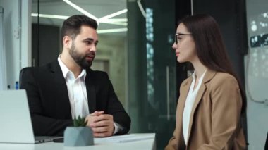 Resmi olarak beyaz erkek ve kadın modern ofiste ciddi bir konuşmadan sonra el sıkışıyor. İki ortak masada oturuyor ve yeni iş projesinde başarılı bir anlaşma yapıyorlar..