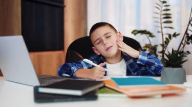 Üzgün, gözleri kapalı bir ilkokul öğrencisi. Evinde ders çalışırken yanağına dokunuyor ve diş ağrısı çekiyor. Günlük giysiler giymiş depresyondaki erkek çocuk hastalık belirtileri gösteriyor..