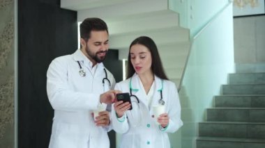 Kafkasyalı esmer kadın klinikte birlikte dikilirken sakallı adama seyyar ekran gösteriyor. Tıp alanında uzman terapistler internette sörf yapıyor ve iş yerinde kahve molası sırasında konuşuyorlar..