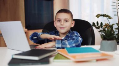 Hevesli beyaz adam rahat koltukta otururken taşınabilir dizüstü bilgisayarın düğmelerini tıklatıyor. Yakışıklı erkek çocuk eğitim ortamında dinleniyor ve gülümseyerek kameraya bakıyor..