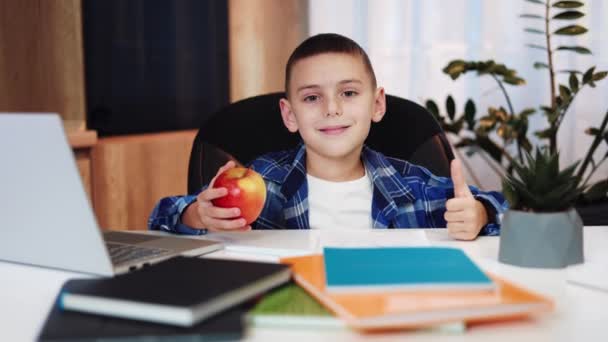 Schoolboy Segurando Maçã Vermelha Sentado Mesa Cheia Livros Coloridos Computador — Vídeo de Stock