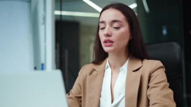 Susamış bir kadının beyaz bluzunu sallarken ve iş yerinde klimasız bir odada dizüstü bilgisayarla otururken sıcak hissetmesini kapat. Kapalı alanda sıcaktan muzdarip yorgun ve güzel bir iş kadını..