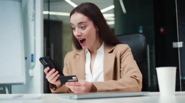 Ofiste online sipariş verirken elinde banka kartı tutan klasik tarz takım elbiseli güzel bir iş kadını. Kafkas tebessüm müdürü modern akıllı telefon kullanarak başarılı internet alışverişi yapıyor..