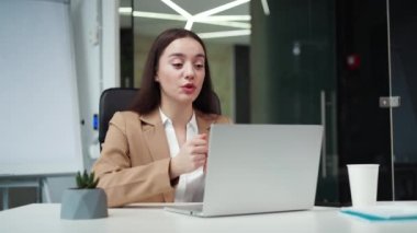 Resmi olarak beyaz, çekici bir iş kadını modern dizüstü bilgisayarda çevrimiçi sohbet sırasında el kol hareketi yapıyor. Yetenekli kadın proje yöneticisi iş yerindeki iş arkadaşlarıyla görüntülü görüşme yapıyor..