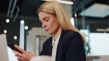 Modern ofisteki güzel odaklı ciddi iş kadını şirket binasında cep telefonu mesajlaşması kullanıyor e-postaları kontrol ediyor iş yerinde başarılı kadın yöneticiler.