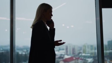 Ofisteki bir iş kadınının silueti akıllı telefon kullanarak telefon görüşmesi yapıyor. Konuşma sırasında, kadın bir müşteri ya da mali danışman ile konuşuyor, bir anlaşma görüşüyor, uzman tavsiyesi veriyor.