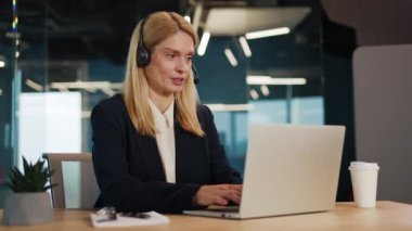 Web kamerası görüntüsü pozitif girişimcinin ofis içindeki iş ekibiyle çevrimiçi görüşmesi. Kablosuz kulaklıklı hoş beyaz kadın yeni projeyi elleriyle işaret ediyor..