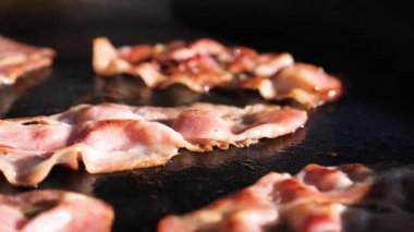 Kavrulmuş domuz pastırmasını ızgara demir tavada yağla pişirme sürecini kapatın. Profesyonel aşçı, uzun ahşap çubuklarla ızgarada yağlı et yapıyor..