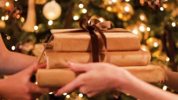 在装饰杉树的背景下 女性的手被紧紧地握住 接受圣诞礼物 女士穿着时髦的晚礼服 给她最好的朋友带了一堆书 — 图库视频影像