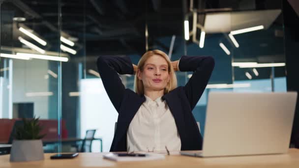 幸せ満足した慎重なビジネス女性は オフィスデスクでリラックスして ノートパソコンの仕事は 仕事でよく行われたストレス解消の心のコンセプトチル作業に満足して頭の後ろに手を置きます — ストック動画