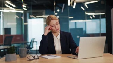 Sıkılmış bir iş kadını, müdür, ofis bilgisayarında online bir proje üzerinde çalışırken yorgun ve ilgisiz görünüyor. Kadın esniyor, can sıkıntısı ve yorgunluk sinyali veriyor ve görünüşe göre enerjiye ihtiyacı var..