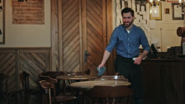 Homem Atraente Limpando Mesas Redondas Café Enquanto Sorri Olha Para — Vídeo de Stock