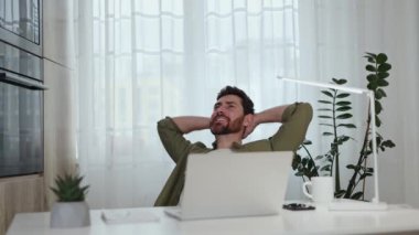 Evdeki ofis masasında otururken yeşil gömlekli mutlu sakallı adam el ele tutuşuyor. Çalışkan Kafkasyalı serbest çalışan, çalışkan bir iş gününden sonra dinleniyor. Çalışma ortamı.