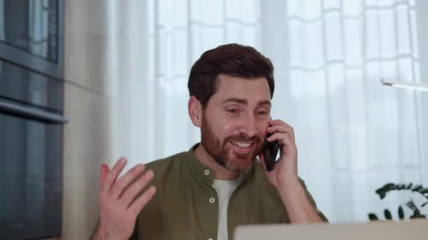 Homem Barbudo Tomando Telefonema Inesperado Rindo Enquanto Sentado Mesa Com — Vídeo de Stock