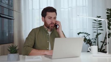 Modern telefonda konuşurken bilgisayar ekranına bakan, başını sallayan ve telefonu kapatan ciddi meşgul bir adam. Çekici girişimci, işvereni evde otururken çalıştırmak için mevcut görevleri anlatıyor.