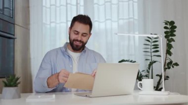 Heyecanlı adam güzel haberlerle kağıt mektubu açıyor ve modern iç ofiste zafer jestiyle evet diyor. Vergi iadesiyle ilgili banka makbuzuyla gelen memnun adam..