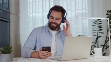 Bilgisayarda çalışmaya başlarken mobil cihazda müzik çalan uzaktan kumandalı tatmin edici kulaklıklar. Gelişmiş çalışan verimliliği ve süreç üzerindeki konsantrasyonu artırmak için rayları kullanıyor.